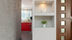 Una cocina moderna con armarios rojos, un estante de vidrio con una planta y una puerta de madera con paneles esmerilados.