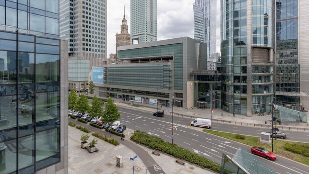 Una calle urbana moderna con edificios altos, una plaza central y una vía despejada.