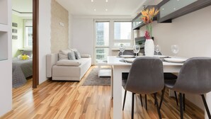Una sala de estar moderna con un sofá, una mesa de comedor con sillas y un ventanal grande.