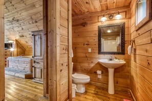 Une salle de bain rustique, aménagée dans une cabane en bois, avec un lavabo, des toilettes et un meuble-lavabo.