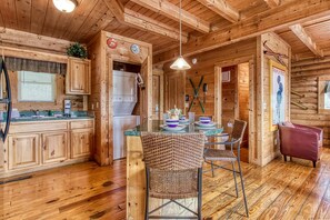 L'intérieur d'un chalet en bois comprend une cuisine, un coin repas et une chaise rouge.