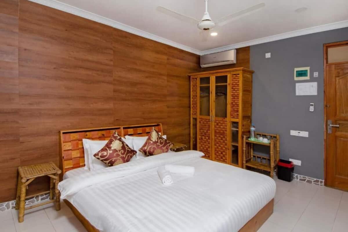A hotel room with a large bed, wooden headboard, and a wardrobe with glass doors.