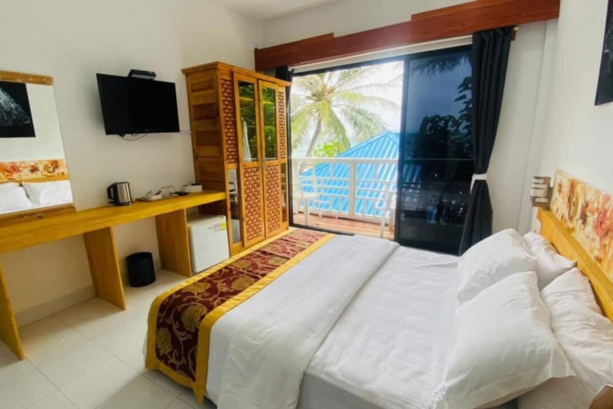 A hotel room with a bed, a desk, a television, and a view of the outside.