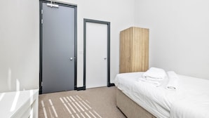 A bedroom with a bed, a wardrobe, a door, and a carpet.
