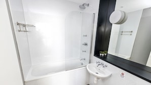 A modern bathroom with a glass-enclosed shower, a white sink, and a black countertop.