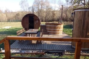 A wooden deck with a table and benches, a barrel-shaped structure, and a cylindrical tank. - 2brcabin-fireplace-hottub-sauna-skiresort (Bran)