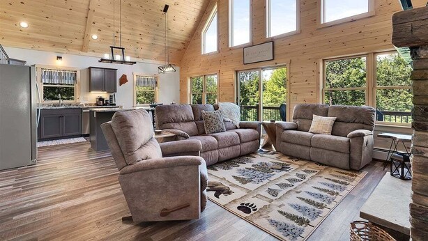 A spacious living room with a large sofa set, a dining area, and a kitchen with a view.