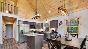 A modern kitchen with a central island, stainless steel appliances, and a dining area with wooden chairs.