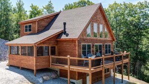 A log cabin with a deck, large windows, and a chimney.