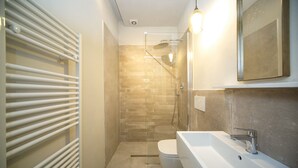 Et moderne badeværelse med bruser, toilet og håndvask.