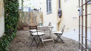En terrasse med et bord og stole, et træhegn og en bygning i baggrunden.
