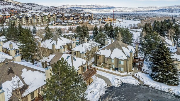 A residential area with snow-covered houses and a mountainous backdrop. - Walk to Ski | Hot Tub | Great Location (Park City)