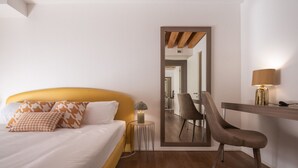 Habitació d'hotel amb un llit, una cadira, un escriptori i un mirall.