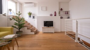 Un saló modern amb una escala, un televisor, una planta en test i un butac armchair groc.