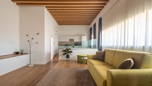 Een moderne woonkamer met een houten plafond, een bank, een salontafel en een keuken op de achtergrond.