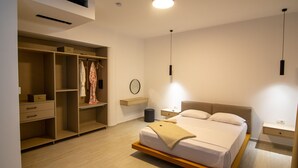 A modern bedroom with a bed, bedside tables, a wardrobe, and a round mirror. - Beautiful 3-bed Villa in Preveza (Preveza)