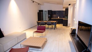 A modern living room with a sofa, a red chair, a wooden coffee table, and a TV on a stand. - Beautiful 3-bed Villa in Preveza (Preveza)