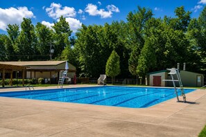 A swimming pool with a lifeguard chair, a covered seating area, and a small building in the background. - The Fawn Château w/ Game Room & sauna  (Lake Ariel)