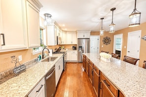 A kitchen with granite countertops, stainless steel appliances, wooden cabinets, and pendant lighting. - The Fawn Château w/ Game Room & sauna  (Lake Ariel)