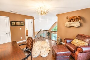 A spacious living room with a wooden dining table, a leather sofa, and a staircase leading to an upper level. - The Fawn Château w/ Game Room & sauna  (Lake Ariel)