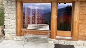 A wooden cabin entrance with a stone wall, a bench, and a large glass door with a curtain. - Chez FOLLO Formidable Mayen in old wood (Mase)