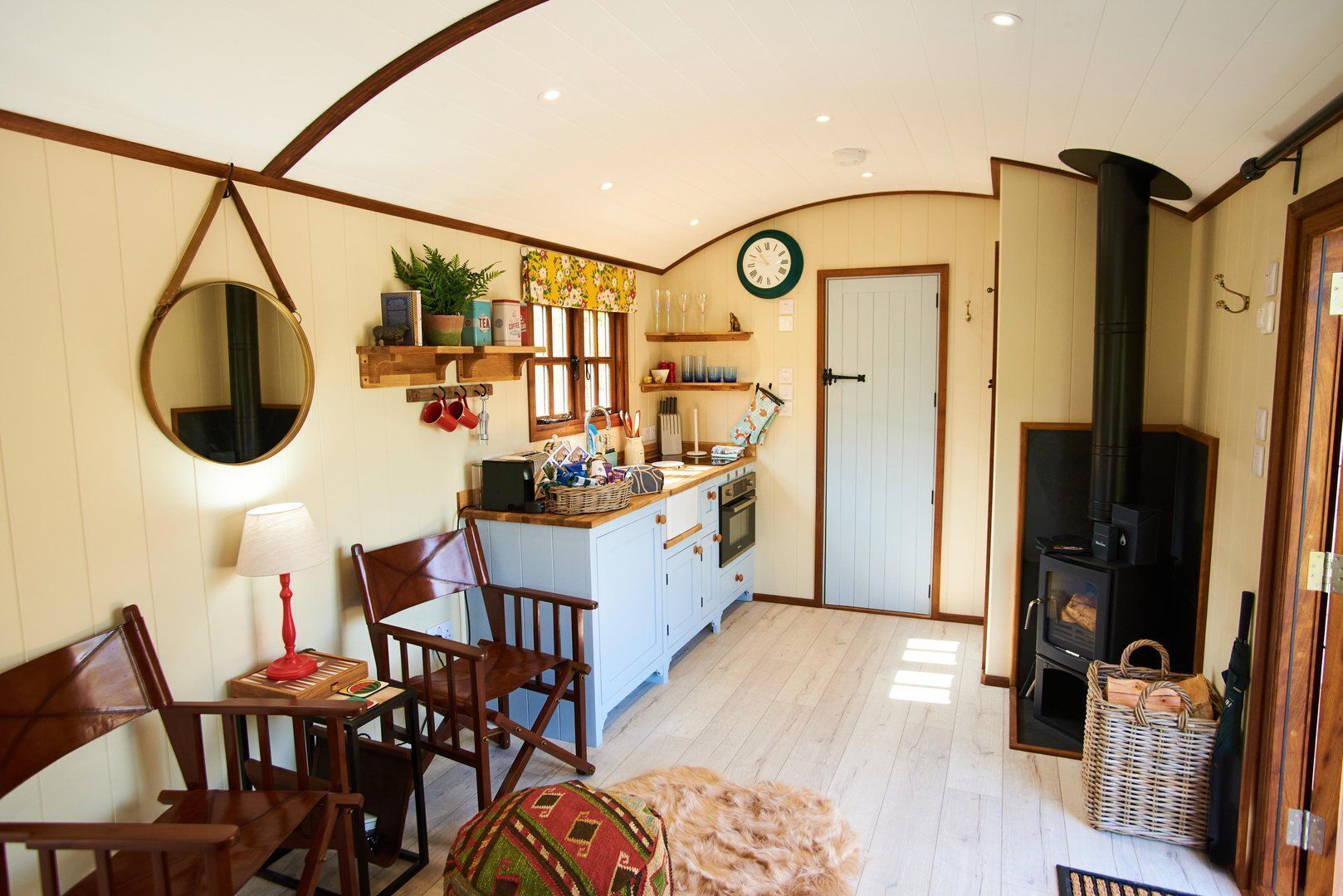 Une cuisine chaleureuse avec des meubles en bois, un coin repas comprenant une chaise et une table, un grand miroir et une cheminée.