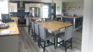 A modern kitchen with a central island, built-in appliances, and a dining area with bar stools.