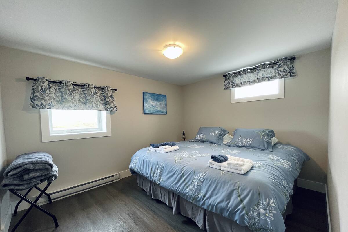 A bedroom with a bed, a chair, a window, and a ceiling light.