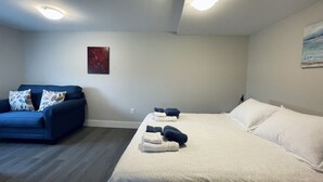 A bedroom with a bed, a blue sofa, and a painting on the wall.