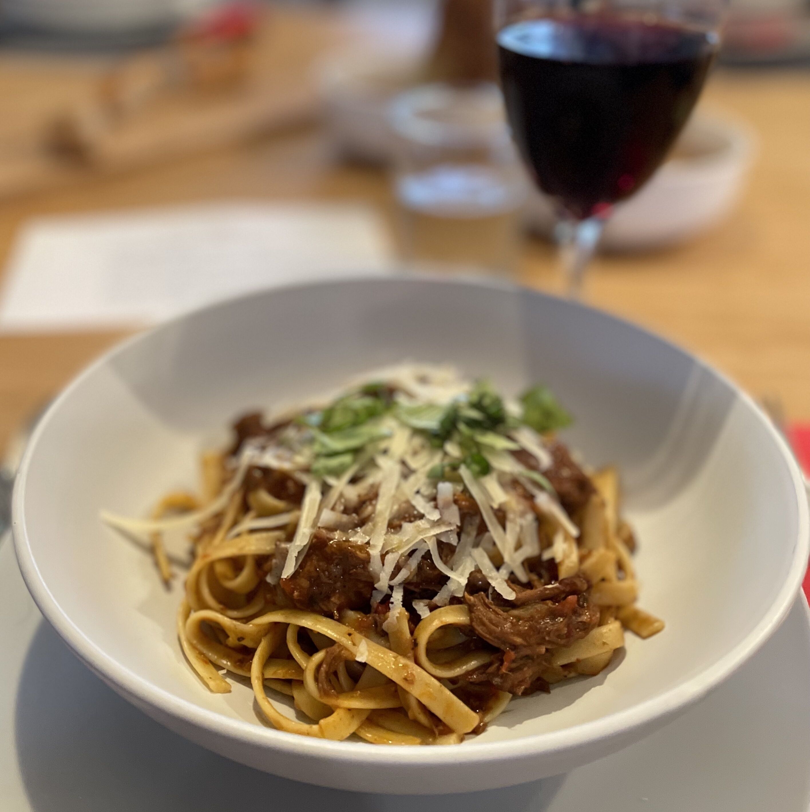 Un plat de pâtes avec de la viande et du fromage, posé sur une table.