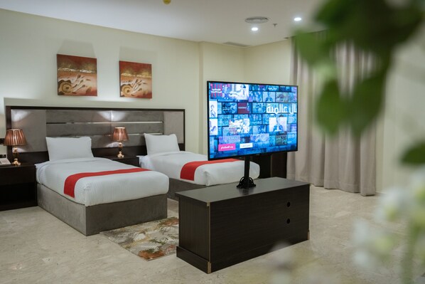 Une chambre d’hôtel moderne équipée de deux lits, d’un téléviseur à écran plat et d’une petite table basse.