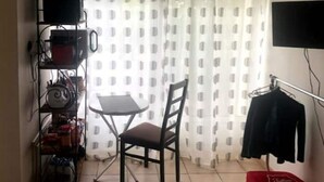 A small room with a chair, a table, a TV mounted on the wall, and a shelf with various items. - Le Nid Castries - Wonderful privated place fully equipped  (Castries)