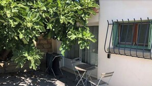 A patio area with a tree, a chair, and a window with a metal grill. - Le Nid Castries - Wonderful privated place fully equipped  (Castries)