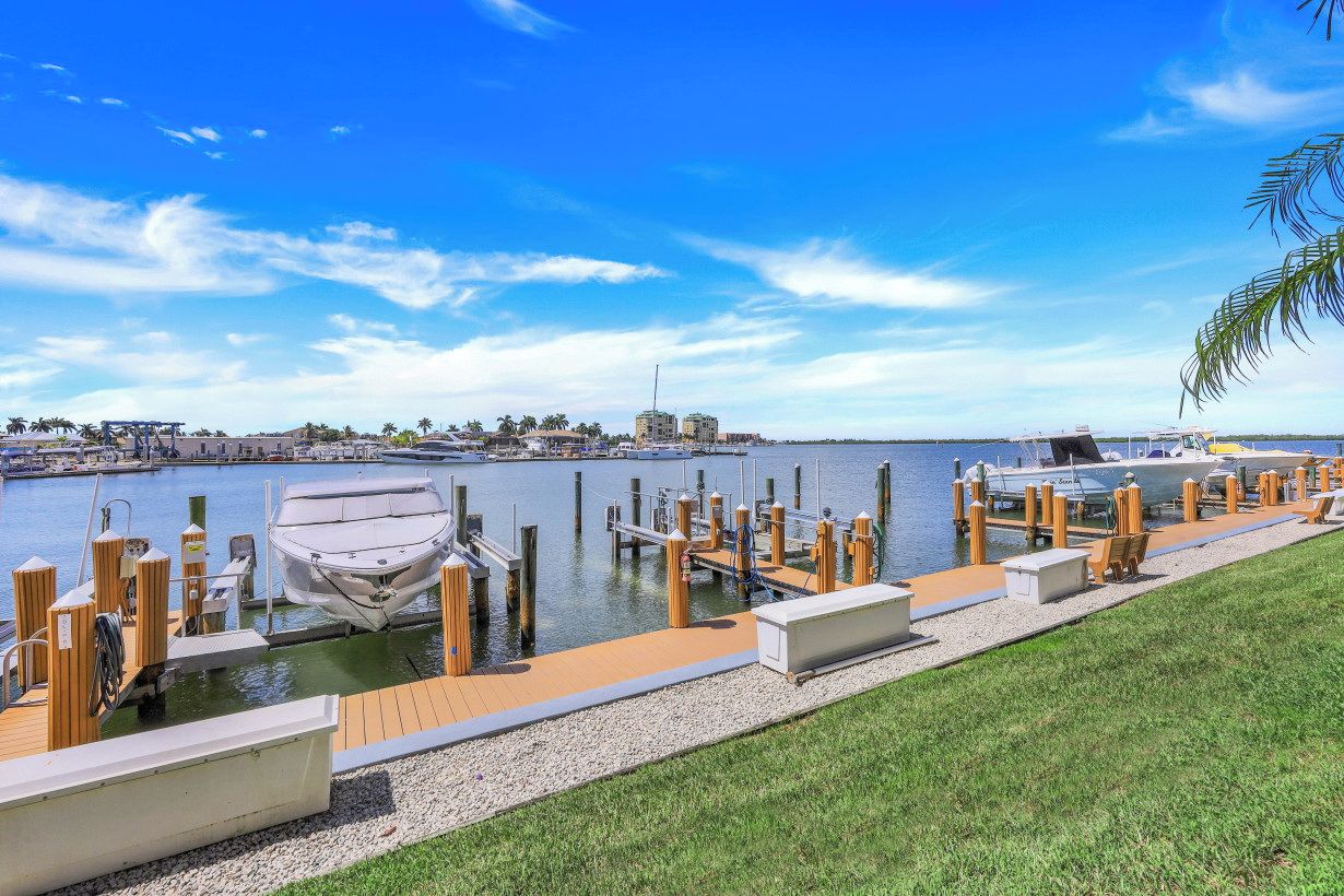 A marina with docked boats, a grassy area, and a clear blue sky.