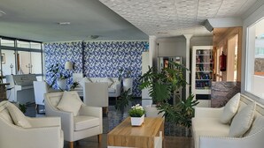 A modern living room with white leather sofas, a wooden coffee table, and a patterned blue and white wall.