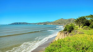 Eine Küstenlandschaft mit Strand, Grünflächen und weite Hügel.