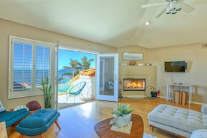 A spacious living room with a fireplace, a television, and a balcony with outdoor furniture.