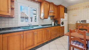 Een keuken met houten kastjes, een spoelbak, een fornuis en een magnetron.