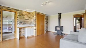 A living room with a sofa, a fireplace, a kitchen area with a sink, and a door leading to another room.