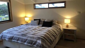 A bedroom with a bed, two bedside lamps, a window, and a ceiling light.