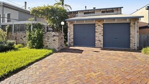 A residential property with a brick driveway, two garage doors, and a well-maintained lawn.