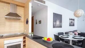 Eine moderne Küche mit Einbauofen, Dunstabzugshaube aus Edelstahl und einem Essbereich mit rundem Tisch und Stühlen.