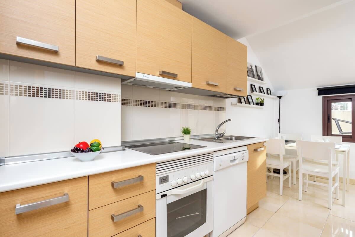 A modern kitchen with wooden cabinets, a white countertop, a built-in oven, and a sink.