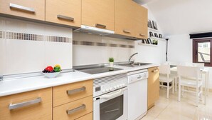 Una cocina moderna con armarios de madera, encimera blanca, horno empotrado y un fregadero.