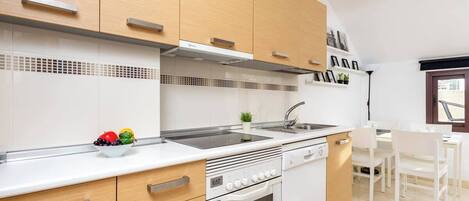 A modern kitchen with wooden cabinets, a white countertop, a built-in oven, and a sink.