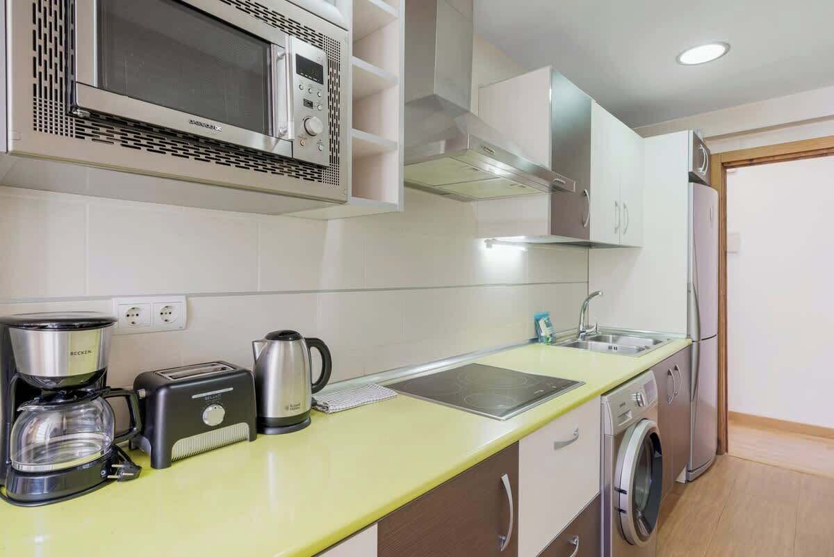 Een moderne keuken met een magnetron, koffiezetapparaat, broodrooster en een wasmachine.