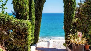 Un sentier menant à un point de vue sur la mer, bordé de haies soigneusement taillées et de plantes en pot.