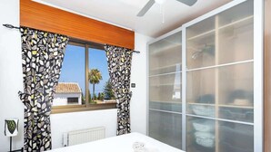A bedroom with a large window, a bed, a radiator, and a wardrobe with sliding doors. - Lovely Apt with Pool by Costarentals - Ref 07 (Málaga)