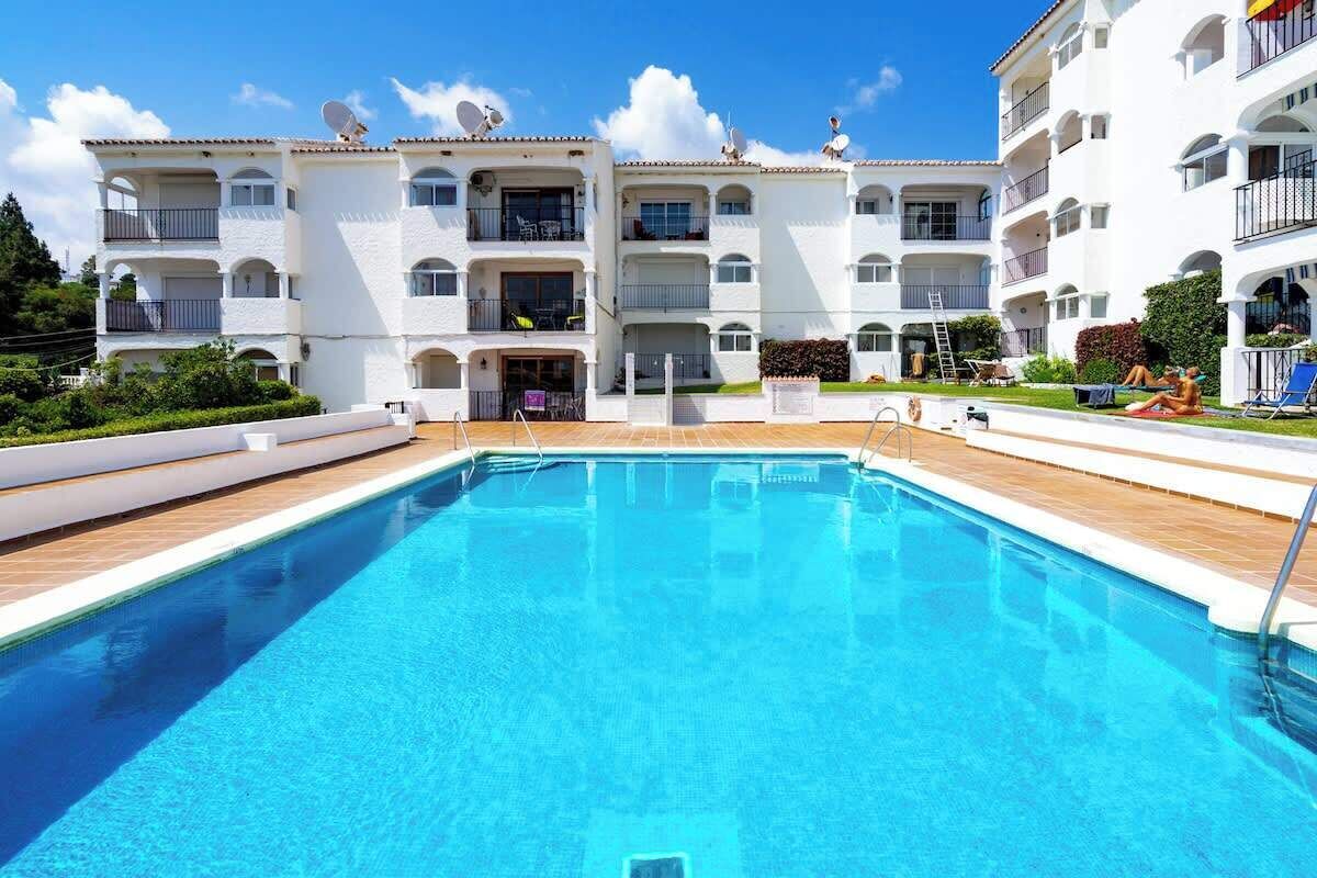 A modern building with a swimming pool, multiple balconies, and a well-maintained garden.