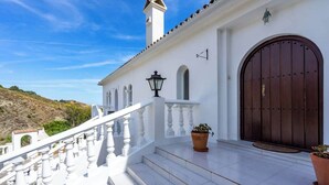 A white building with a large wooden door, a white staircase, and a view of a hilly landscape. - Villa Sabah with sea views near Mijas Pueblo - REF 119 (Mijas)